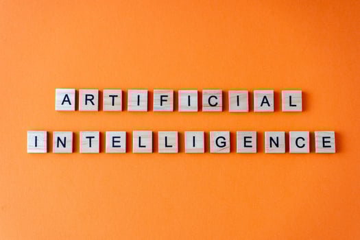 Word artificial intelligence. The phrase AI is laid out in wooden letters top view. Orange flat lay background. photo