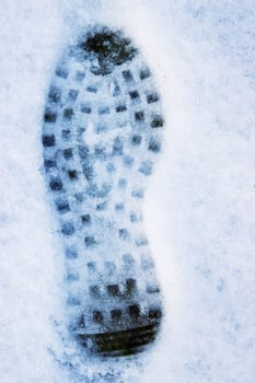 Closeup of a single black footprint in a white snow left by a boot, symbolizing color and texture contrast and outdoor adventure on a cold winter day. Copy space photo