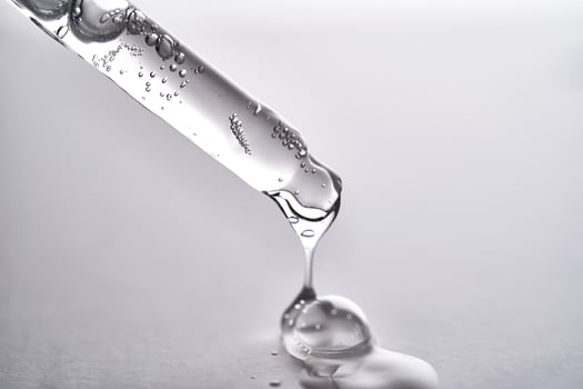 Pipette with facial serum pouring out of it on grey background. photo