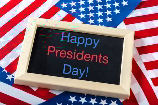 the text happy presidents day written in a chalkboard and a flag of the United States photo
