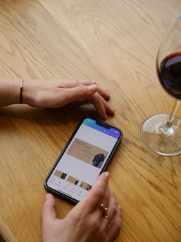 A woman's hand holding a smartphone and a glass of red wine photo