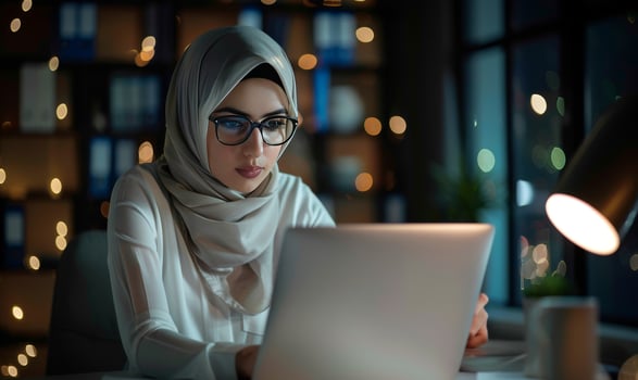Arab woman with laptop. Arabian girl in islamic in business office at work. Beautiful female businesswoman person. Muslim freelancer in headscarf sitting at computer photo