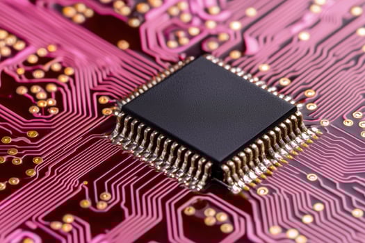 Closeup of a black computer chip on a pink circuit board photo