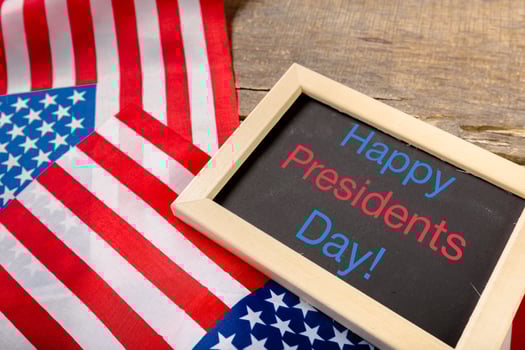 the text happy presidents day written in a chalkboard and a flag of the United States photo