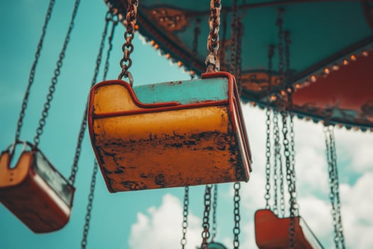 A close-up of a vintage, rusty carousel swing seat with a bright blue sky in the background. photo