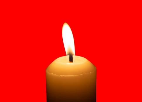 A single burning candle flame or light glowing on a big white candle isolated on red background with clipping path photo