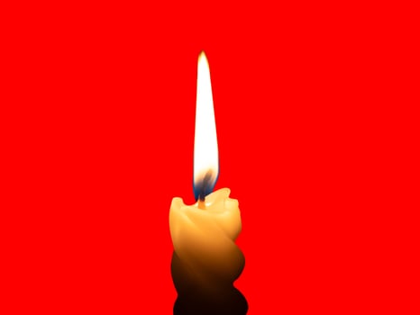 A single burning candle flame or light glowing on a small spiral yellow candle isolated on red background with clipping path photo