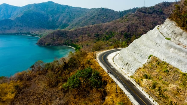 A stunning view of hills in Sumbawa, leading towards Mount Tambora. The vibrant blue sea stretches alongside, creating a breathtaking coastal landscape. photo