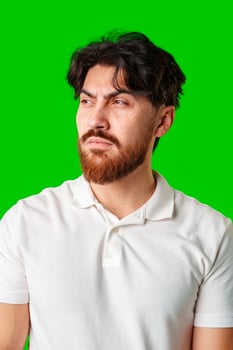 A man with a serious expression stands with crossed arms against a vibrant green background photo