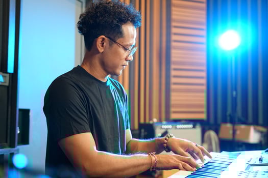Musician playing music keyboard, Asian man playing piano and practicing in home studio photo