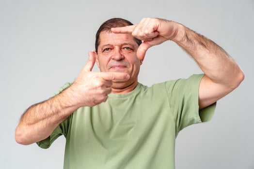 A man demonstrates framing a shot with his hands in a studio setting photo
