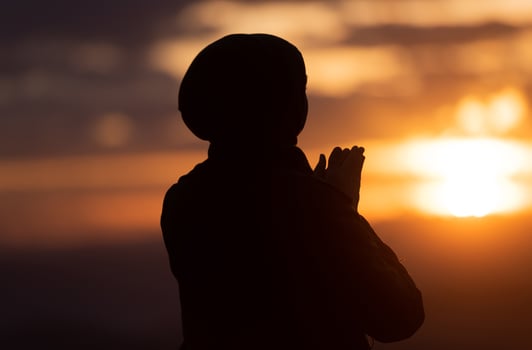 Silhouette of Muslim woman prayer having worship and praying with hands for thank god Allah at sunset. photo