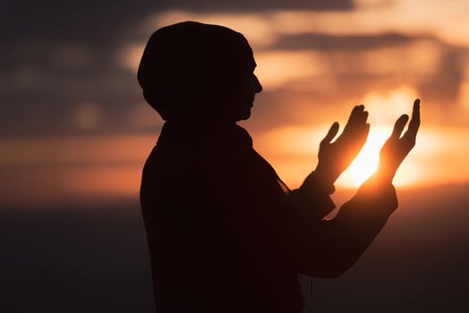 Muslim woman prayer praying with hands up open doing dua at sunset worship Allah. photo