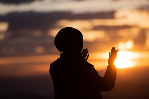 Muslim woman prayer praying with hands up open doing dua at sunset worship Allah. photo