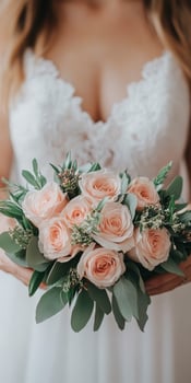 A bride holds a delicate bouquet of pink roses in a soft dress photo