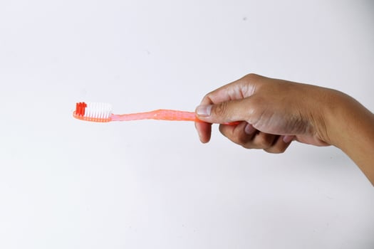 Male hand holding an orange toothbrush on a white background photo