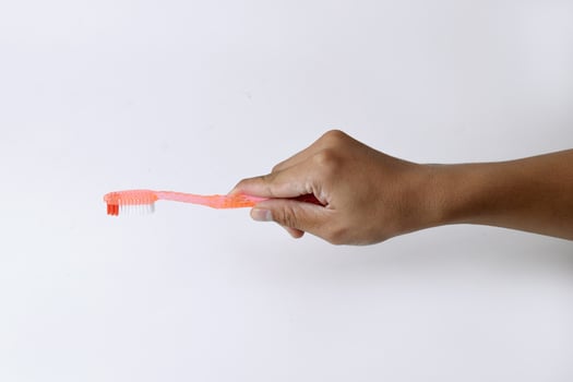 Male hand holding an orange toothbrush on a white background photo