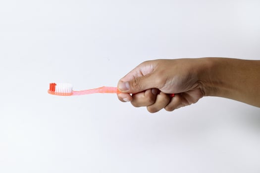 Male hand holding an orange toothbrush on a white background photo