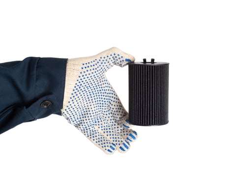 An auto mechanic holds in his hand an old dirty oil filter on a white background, isolate. Car oil and filter replacement concept, replacement schedule photo