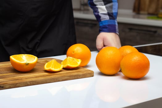 A man cuts with a knife in the kitchen juicy and fresh oranges. The concept of healthy eating and making orange juice, copy space photo