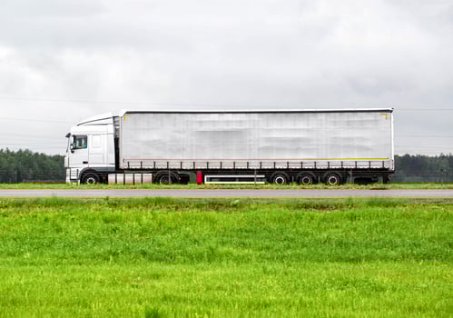 A beautiful modern semi-trailer truck transports cargo in rainy weather. Side view. Freight transportation services, import substitution. Copy space for text. Freight market photo