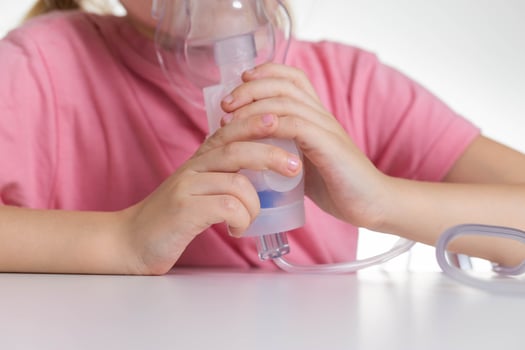 A 5-year-old girl breathes into an inhaler to dilute sputum in case of lung diseases. Treatment of cough in children. Nebulizer therapy photo