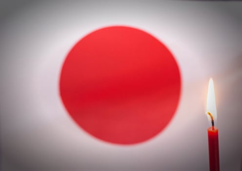 Burning candle on the background of the flag of Japan. The concept of mourning and sorrow in the country, terrorism photo