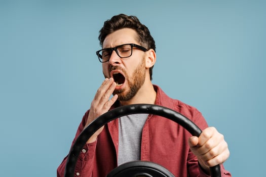 Portrait tired bearded, Latin man wearing eyeglasses yawning holding steering wheel photo