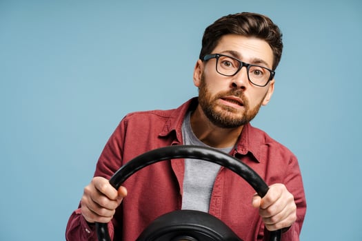Portrait of a worried, middle aged Latin man wearing eyeglasses holding steering wheel photo
