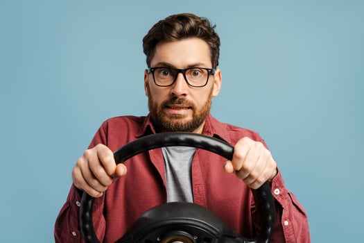 Portrait of worried, middle aged Latin man wearing eyeglasses holding steering wheel photo