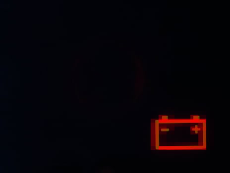 Red battery icon on a black background. Car battery discharge concept, copy space for text photo