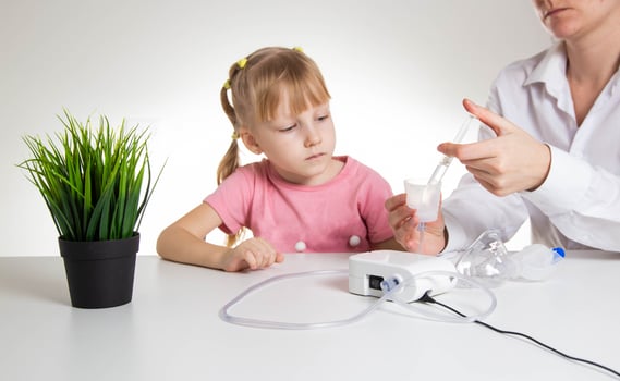 A doctor is putting a drug into a nebulizer for the treatment of respiratory diseases in a little girl 5 years old. Inhalation for the treatment of bronchitis and pneumonia photo
