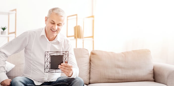 Good memories concept. Happy mature man holding frame, looking at photo of his kids and grandchildren, free space