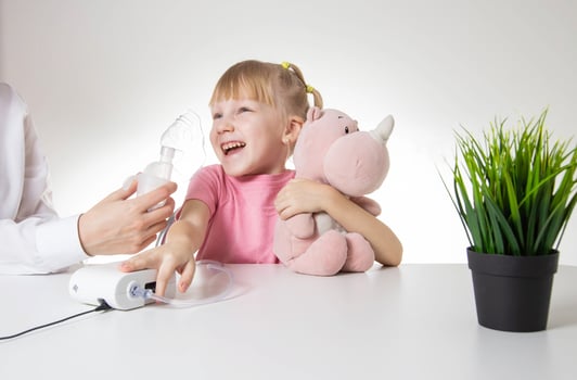 A little girl 5 years old in a pink T-shirt breathes into a nebulizer for lung disease. Treatment of bronchitis with inhalation, pharyngitis photo