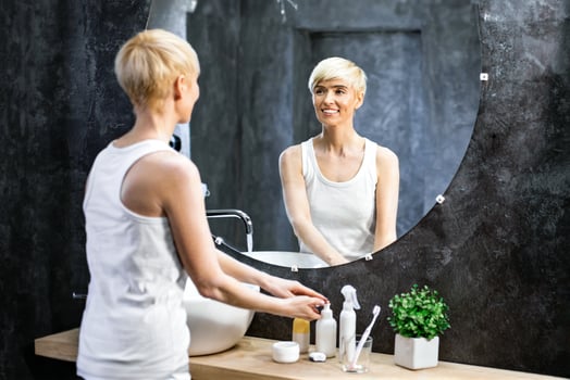 Middle-Aged Woman Washing Hands Standing In Bathroom. Hygiene And Skincare. Panorama, Copy Space, Selective Focus photo