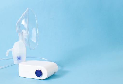 A nebulizer treatment device for the treatment of airway inflammation, cough and pneumonia. Prevention of bronchial asthma, blue background, copy space, healthcare photo