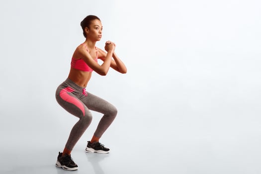 Fitness And Sport. African American Woman Doing Deep Squat Exercising On Pink Studio Background. photo