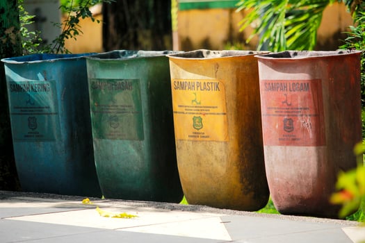 A row of colorful trash bins for waste segregation in an outdoor park setting, promoting eco-friendly practices photo