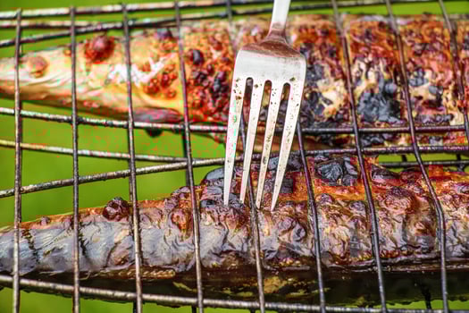 The process of cooking mackerel fish in a marinade on the grill. Fried fish is ready. photo