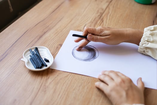Woman Sketching Circle on Paper at Wooden Desk photo