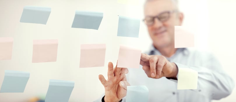 Presentation Concept. Successful middle-aged business man putting his ideas on sticky notes in conference room photo