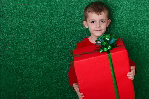 portrait cute boy holding a gift in his hands. green background. christmas concept. Celebrate birthday. Grateful for good gift. Unexpected surprise photo