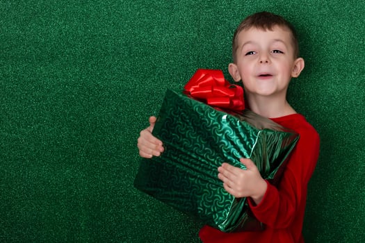portrait cute boy holding a gift in his hands. green background. christmas concept. Celebrate birthday. Grateful for good gift. Unexpected surprise photo