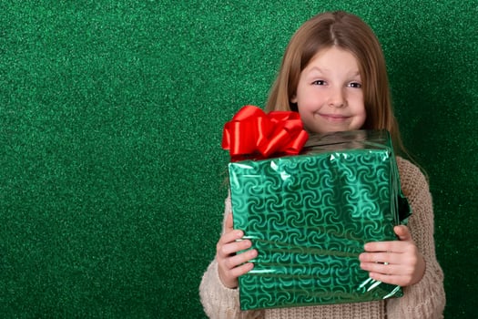 portrait cute girl holding a gift in his hands. green background. christmas concept. Celebrate birthday. Grateful for good gift. Unexpected surprise photo
