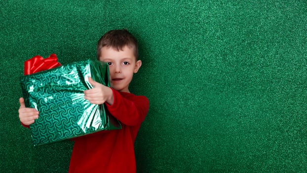 portrait cute boy holding a gift in his hands. green background. christmas concept. Celebrate birthday. Grateful for good gift. Unexpected surprise photo