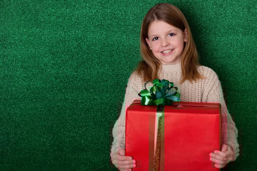 portrait cute girl holding a gift in his hands. green background. christmas concept. Celebrate birthday. Grateful for good gift. Unexpected surprise photo