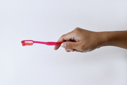 Male hand holding a red and white toothbrush containing toothpaste photo