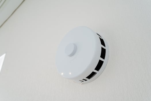 White smoke detector, hanging on wall, blends with wood, metal, circle design photo
