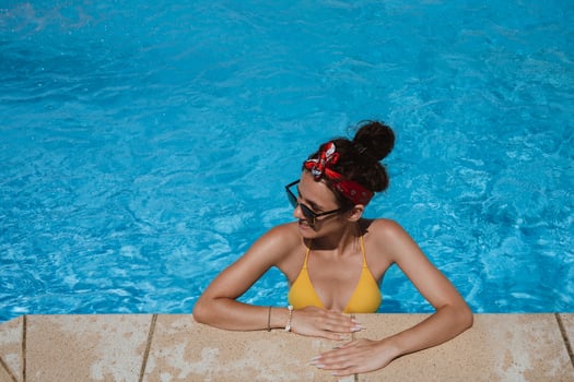 An attractive young Caucasian woman, leaning on the edge of the pool photo