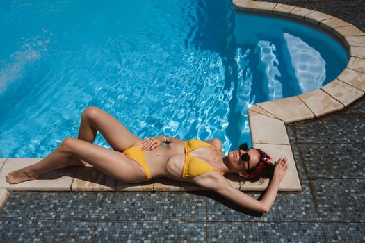 Model woman in sunglasses and yellow bikini relaxing in swimming pool. photo